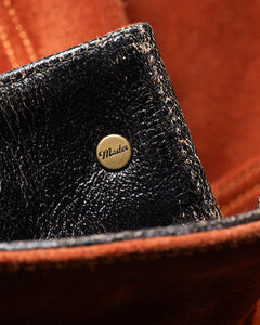 Close-up of Master Supply Co men's brown leather jacket interior rivet with Master logo